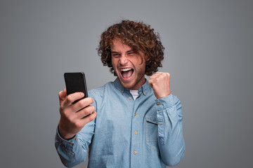 Male with smartphone celebrating success