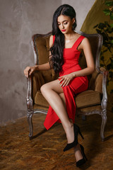a beautiful woman with a red dress sits on a chair, a beautiful make-up and bright red lips