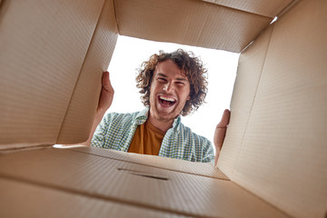 Cheerful man looking inside open box