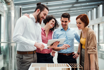 Group of young businesspeople standing near a staircase, talking.