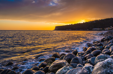 Panorama view of amazing ocean scenery with rocks on a beach in beautiful golden evening light at sunset