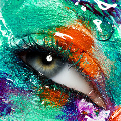 Fashion and beauty. Perfect female face. Colorful body art and artistic liquid makeup. Macro shot. Closeup of beautiful female eye with creative, colorful makeup