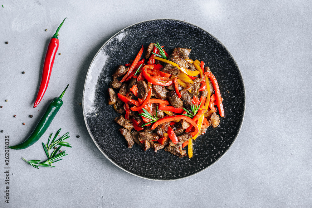 Poster Asian cuisine beef with red and yellow paprika peppers in teriyaki sauce top view