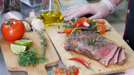 A chef working in the kitchen. A man serving a steak