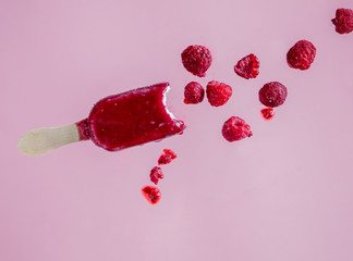 raspberries ice lolly in air on pink background
