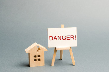 Shabby housing. Inscription Danger. The concept of an emergency house. Old house from which...