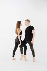 Obraz na płótnie Canvas Professional Caucasian Dance Couple Stand Posing. Beautiful Brunette Slim Female Dancer Looking at Blond Male Partner. Contemporary Duet Wear Black Form Side View Isolated on White Background