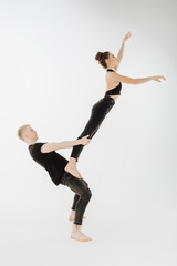 Modern Ballet Couple do Dance High Level Lift. Man in Demi Plie, Woman Dancer Stand on his Hip do Arabesque. Young Perfomer in Black Form do Sensual Movement Isolated on White Background