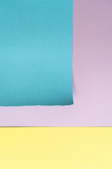 Vertical purple-blue-yellow paper background. A piece of blue paper with torn edges and yellow stripe on the background of a sheet of purple paper