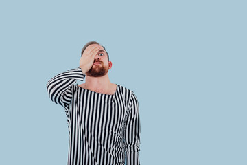 young man, concept of prisoner, in prison clothes, isolated blue background, copy space