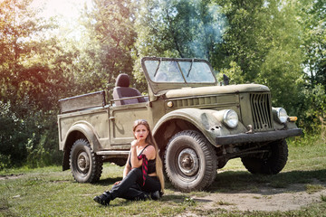 Fototapeta premium Woman sitting on the ground near military car