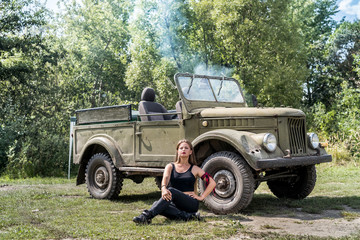 Woman sitting on the ground near military car