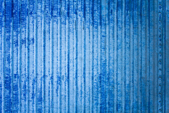 old white blue battered metal fence wall with damages and rivets. vertical lines. rough surface texture © Pavel