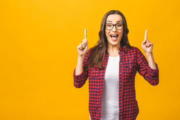 Great idea! Happy smiling beautiful young woman showing copyspace, visual imaginary or something, or pressing virual button isolated over yellow background.