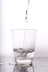 water pouring into a glass isolated on white background