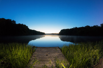 Fototapeta na wymiar Peaceful night scene of a calm forest lake and a starry sk