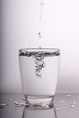 water pouring into glass on white background