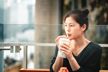 Young woman drinking coffee and eating a delicious muffin cake in cafe,