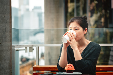 Fototapeta premium Young woman drinking coffee and eating a delicious muffin cake in cafe,