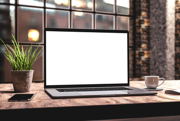 Laptop with blank screen mockup template on table in industrial old factory loft interior - front...