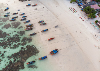 Wooden long-tail boats anchor on coastline with coral reef in sea