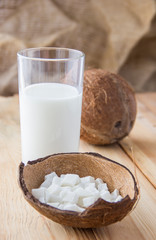 Coconut slices and a glass of milk.Coconut on a wooden table.Vegan non dairy healthy drink