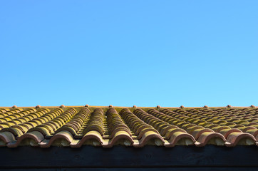 Low angle view of tile  roof  building against clear blue sky .