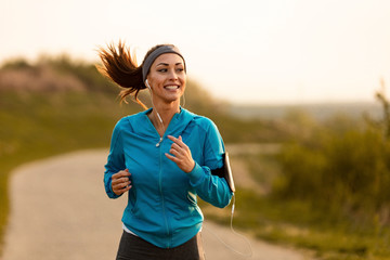 Happy female runner jogging in the morning in nature. - obrazy, fototapety, plakaty