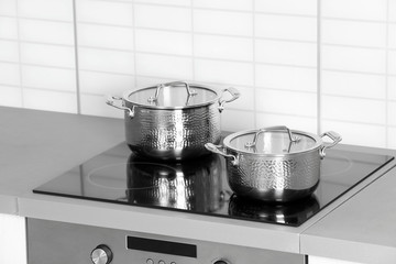 Clean pans on modern stove in kitchen