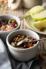 Healthy breakfast.Two bowls of muesli with oats, nuts and dried fruits - apples, resins, pumpkin seeds and almonds on wooden table. Top view. Rustic style.