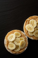 Peanut butter and banana on rice cakes, healthy, dietary food. Black background.