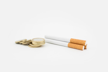 Several cigars and a stack of coins on white background. Economic expenditure.