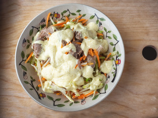 Easy deethic salad of green radish, carrots and turkey, seasoned with a spicy vegetable coax on a wooden kitchen board.
