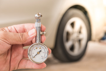 Tire gauge in hand. Blur the wheel as the background.