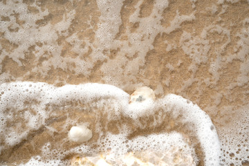 sea wave with bubbles on the sand beach