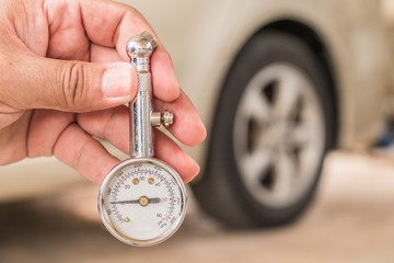 Tire gauge in hand. Blur the wheel as the background.