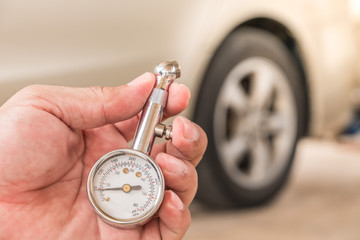 Tire gauge in hand. Blur the wheel as the background.