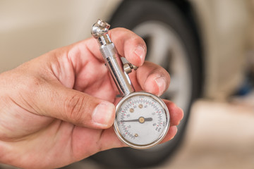 Tire gauge in hand. Blur the wheel as the background.