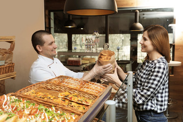 Woman buying tasty pastry in bakery shop