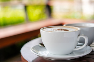 Hot coffee and hot tea place on the wooden table in early morning with copyspace, white cup and silver spoon.