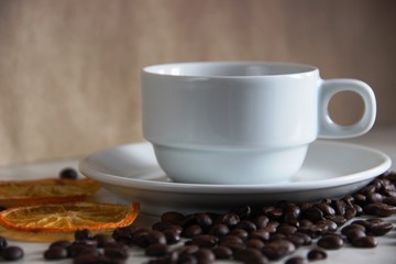 white classic cup and saucer, coffee beans and dried orange mugs, close-up. classic love of coffee and citrus, selective focus.