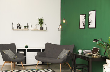 Modern living room interior with workplace near green wall