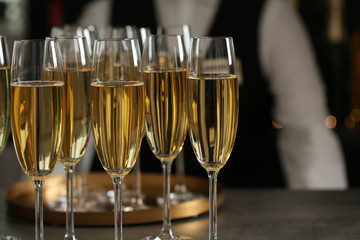 Glasses of champagne and waiter in restaurant, closeup