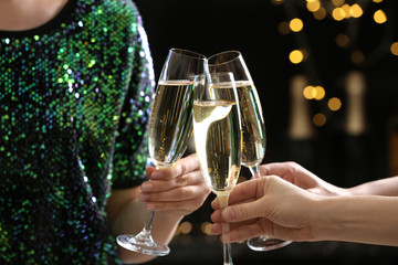 People clinking glasses of champagne on blurred background, closeup