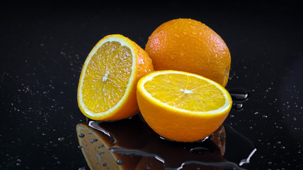 Fototapeta na wymiar Fresh oranges on black background sliced orange water pouring on fruits
