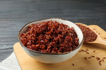 Board with bowl of boiled brown rice on table