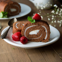 Delicious chocolate roll sponge cake with vanilla cream and mint leaves. Desert sweet food.