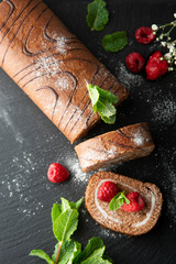 Delicious chocolate roll sponge cake with vanilla cream and mint leaves. Desert sweet food.