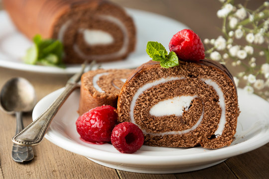 Delicious chocolate roll sponge cake with vanilla cream and mint leaves. Desert sweet food.