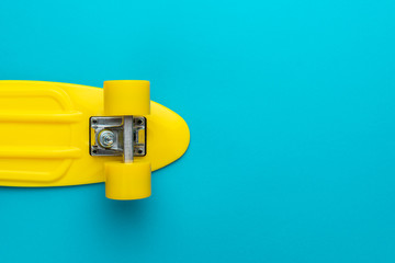 minimalist flat lay photo of cruiser skateboard over turquoise blue background © Ruslan Grumble
